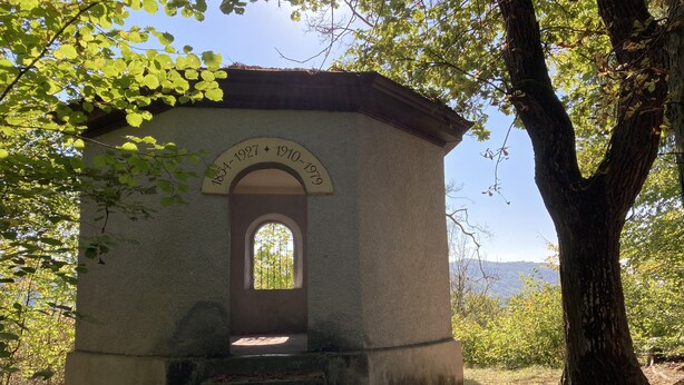 Un petit bâtiment rustique à la façade en pierre, doté d’une entrée en arc de cercle et d’une plaque commémorative indiquant son importance historique.