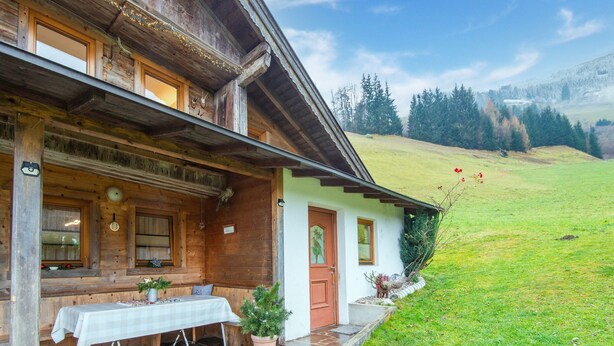 Un chalet in legno con un patio in pietra, un tavolo con tovaglia e un albero di Natale.