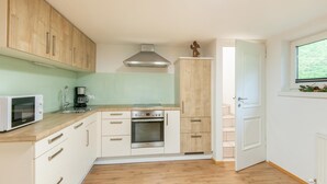 Una cucina compatta con mobili in legno, un forno a microonde, un fornello e una finestra con vista sul verde.