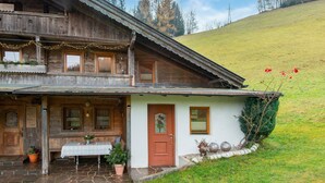 Un chalet in legno con un balcone, un ingresso con pavimento in pietra e un piccolo tavolo con tovaglia.