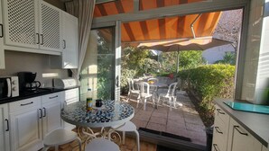 A compact kitchen with white cabinets, a microwave, a coffee maker, and a table with chairs.