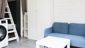 A compact living space with a blue sofa, a white coffee table, a washing machine, and a white wardrobe. - Nice studio  - 2P - near Paris (Ivry-sur-Seine)
