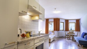 A compact kitchen with a stove, sink, and a dining area with a table and chairs. - Apartment Neustift Near Stubai Glacier (Neustift Im Stubaital)