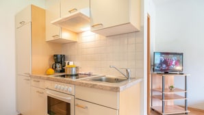 A modern kitchen with a built-in oven, a sink, and a coffee maker. There's a television on a stand to the right. - Apartment Neustift Near Stubai Glacier (Neustift Im Stubaital)