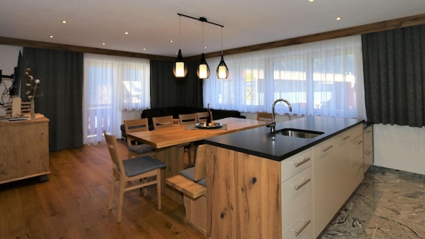 Una cocina moderna con isla de madera, armarios empotrados e iluminación colgante.