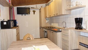 A compact kitchen with wooden cabinets, a built-in microwave, a gas stove, and a coffee maker. - Apartment in Hippach With Mountain Views (Hippach)