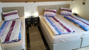 A hotel room with two beds, each with patterned bedding and headboards. There are bedside tables with lamps and a small rug on the floor. - Apartment in Hippach With Mountain Views (Hippach)