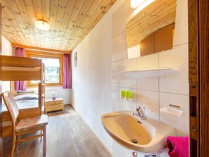 A wooden interior with a bunk bed, a sink, and a window with curtains. - Scenic Apartment in Tirol With Garden (Kaltenbach)