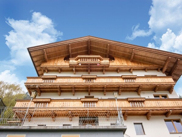 A multi-story building with a wooden facade, balconies, and a clear sky. - Scenic Apartment in Tirol With Garden (Kaltenbach)