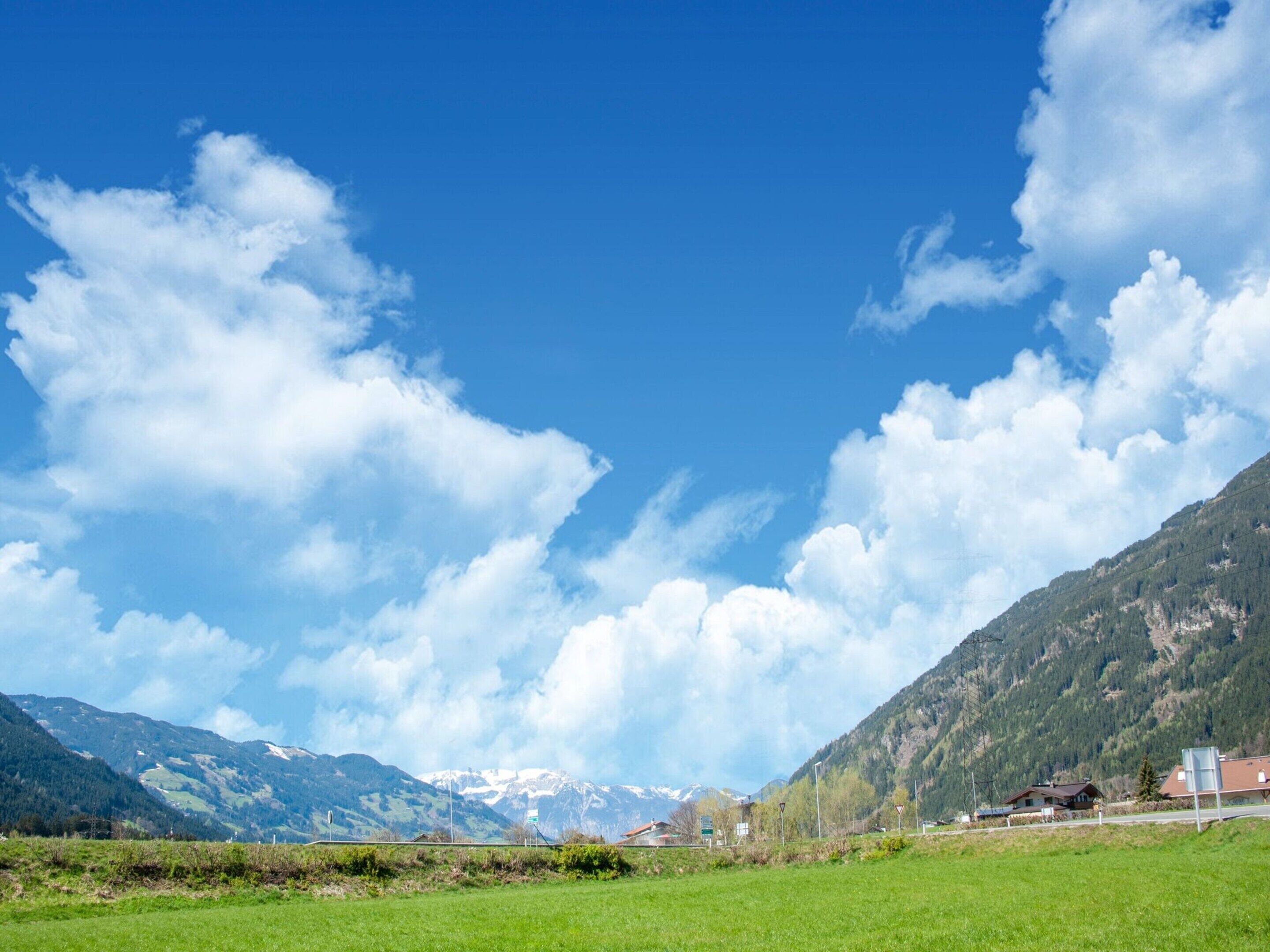 A rural landscape with a clear sky, green fields, and distant mountains.