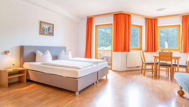 Quarto de hotel com uma cama, uma escrivaninha e uma cadeira.