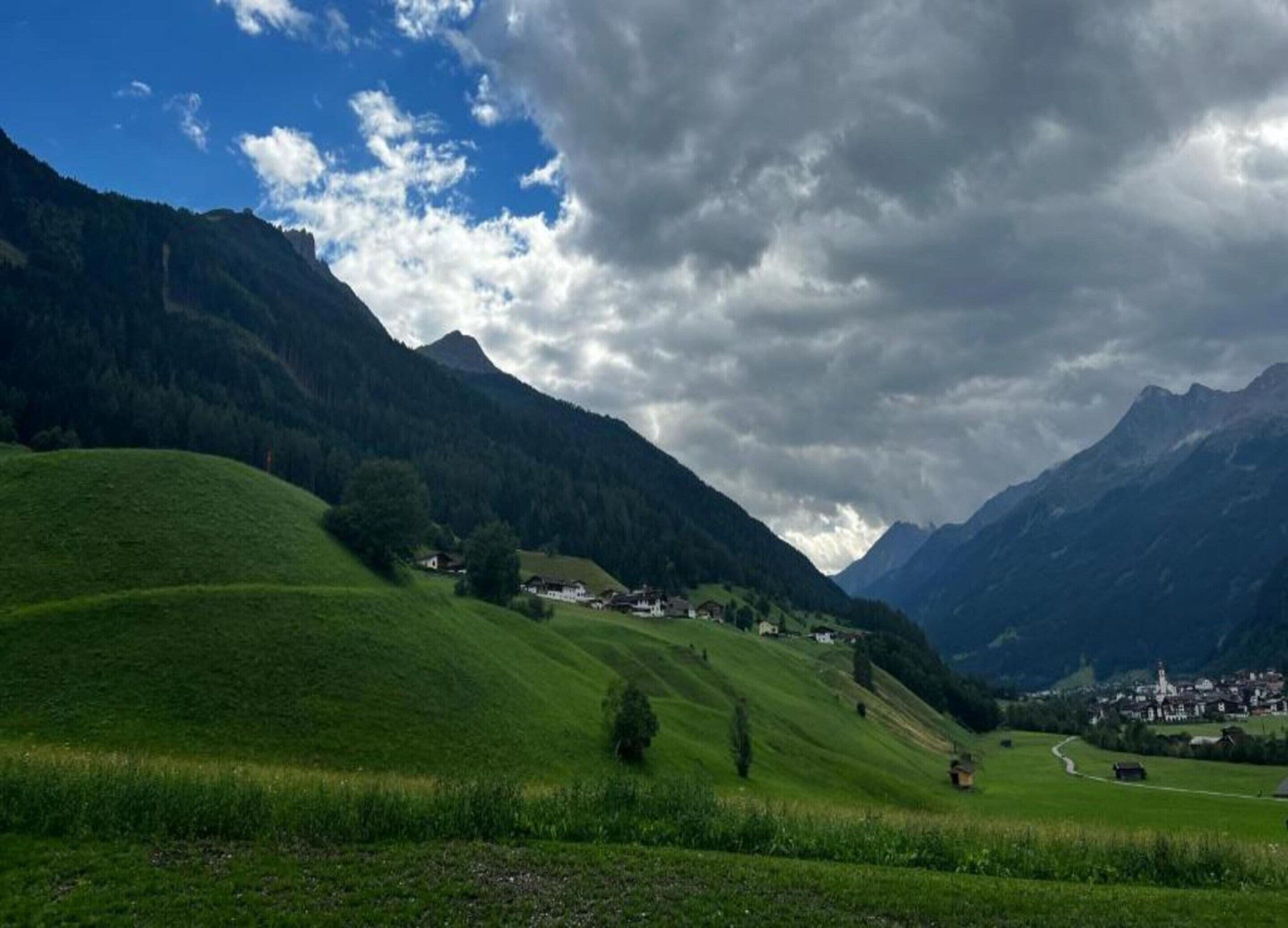 A mountainous landscape with green fields and a small village.