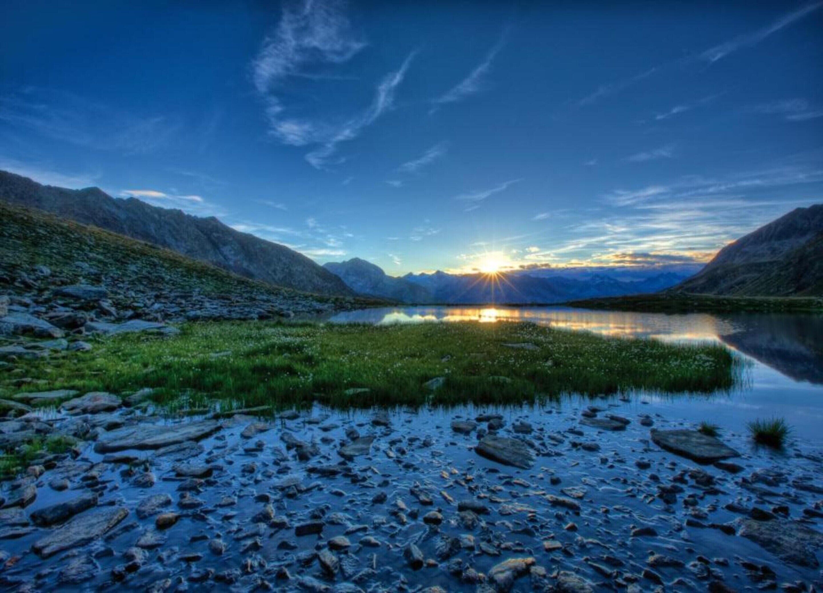 Un paysage montagneux avec un lac reflétant le coucher de soleil.