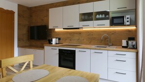 A modern kitchen with white cabinets, a built-in microwave, a sink, and a wooden countertop. - Apartment Neustift Near Stubai Ski Lift (Neustift Im Stubaital)