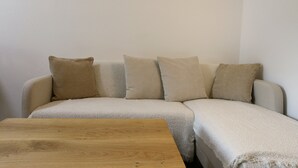 A beige sofa with four cushions against a plain wall. In front of the sofa is a wooden coffee table. - Apartment Neustift Near Stubai Ski Lift (Neustift Im Stubaital)