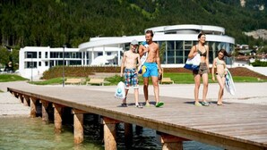 A wooden pier extending over water with a modern building in the background. - Charming Holiday Home in Maurach am Achensee (Eben am Achensee)