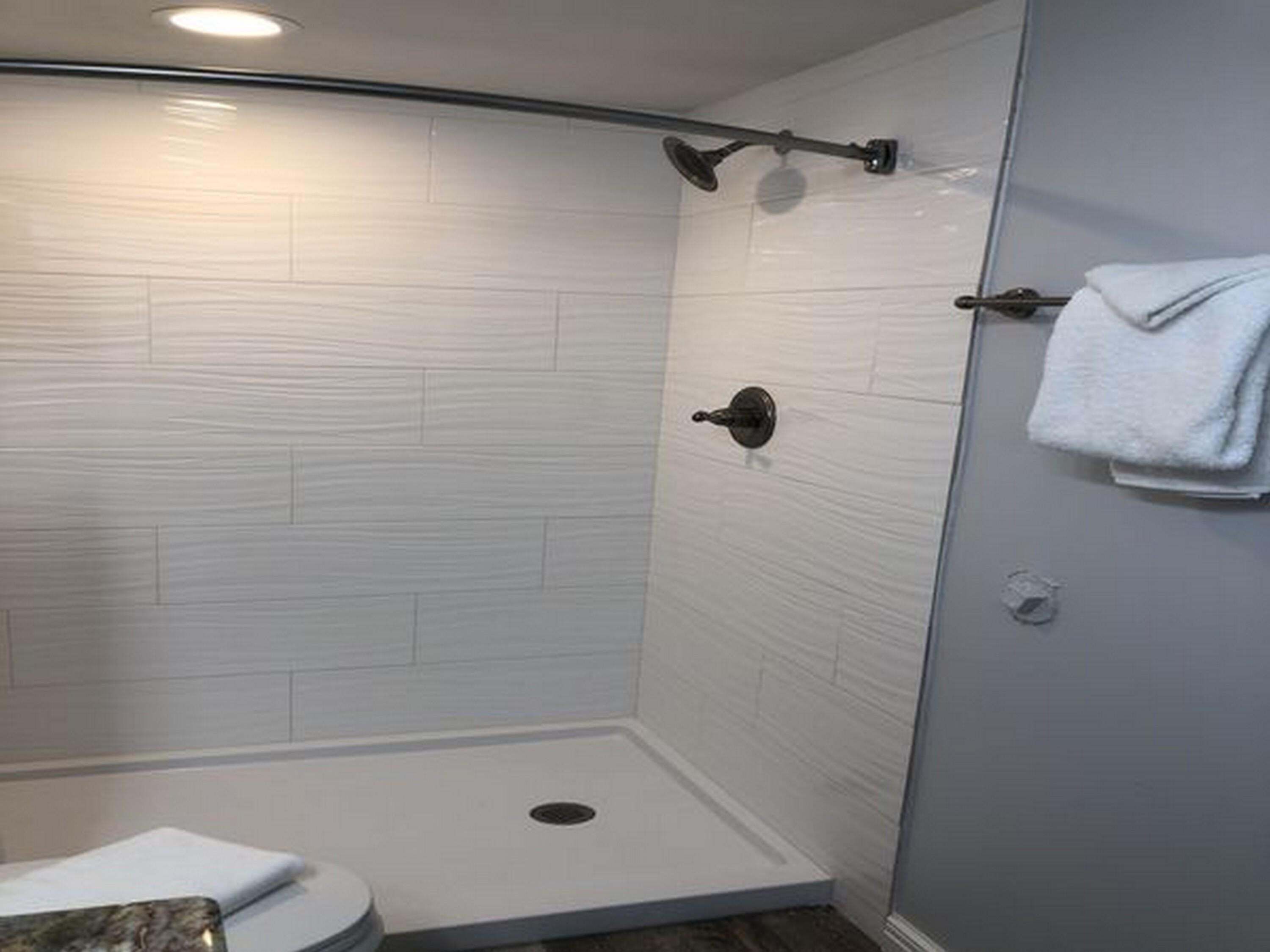 A modern bathroom with a shower, toilet, and towel rack.