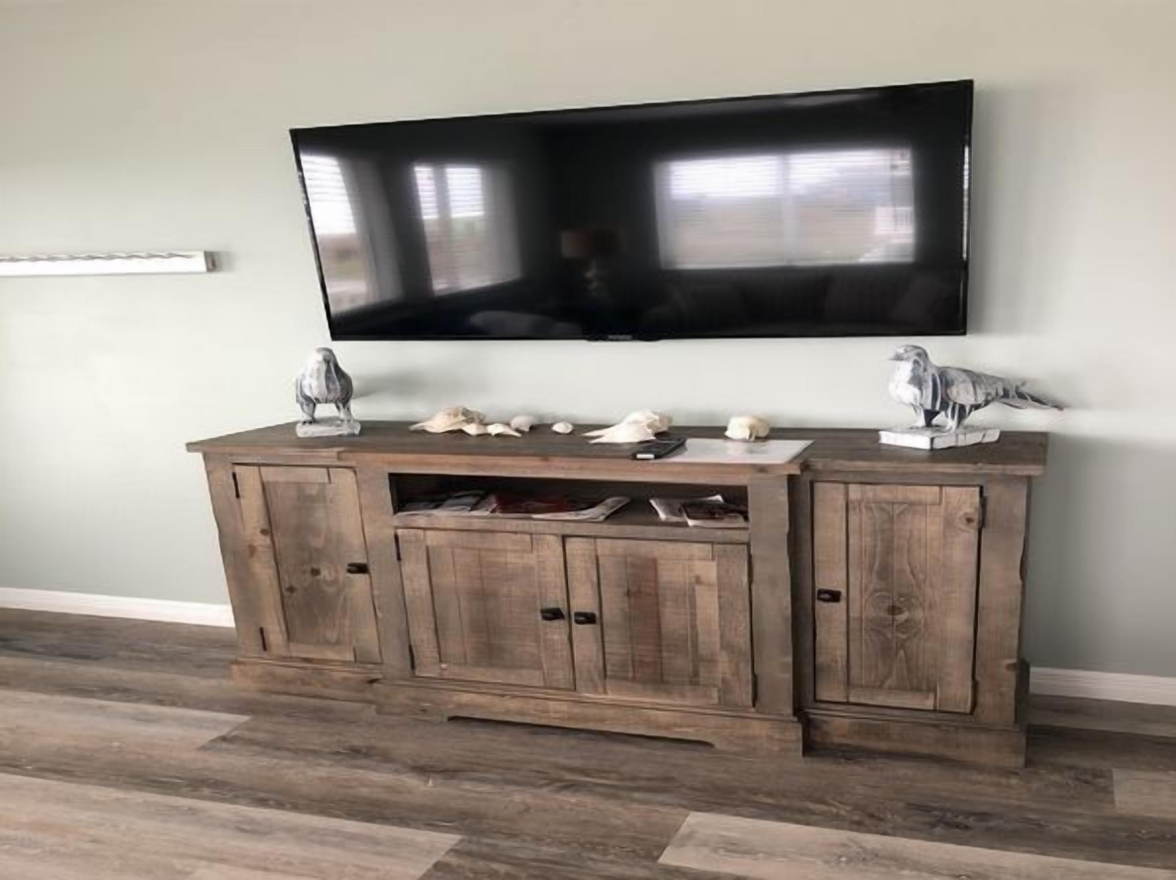 Un mueble de entretenimiento de madera con un televisor de pantalla plana montado encima.
