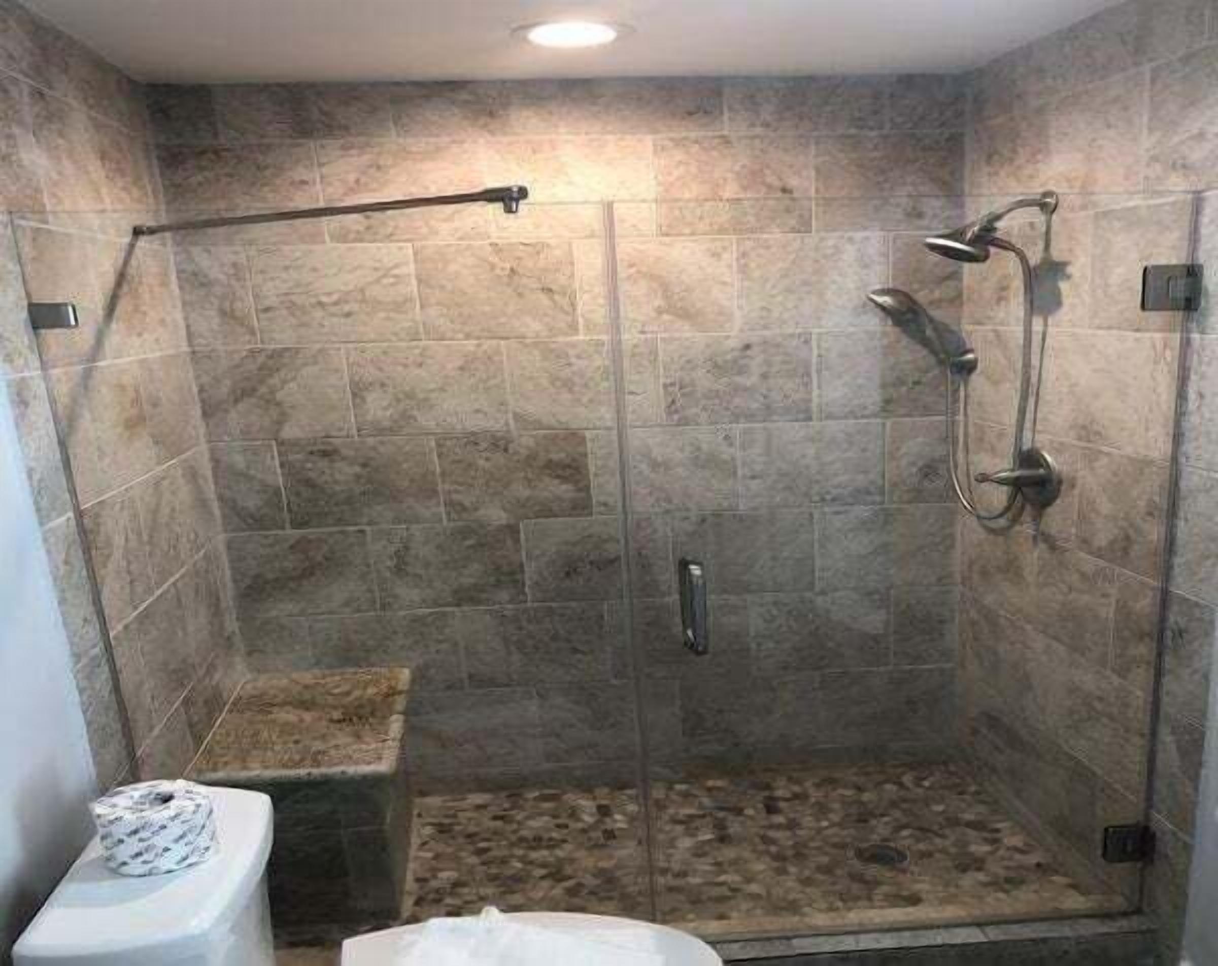 A shower with a glass door, a handheld showerhead, and a handheld shower attachment.