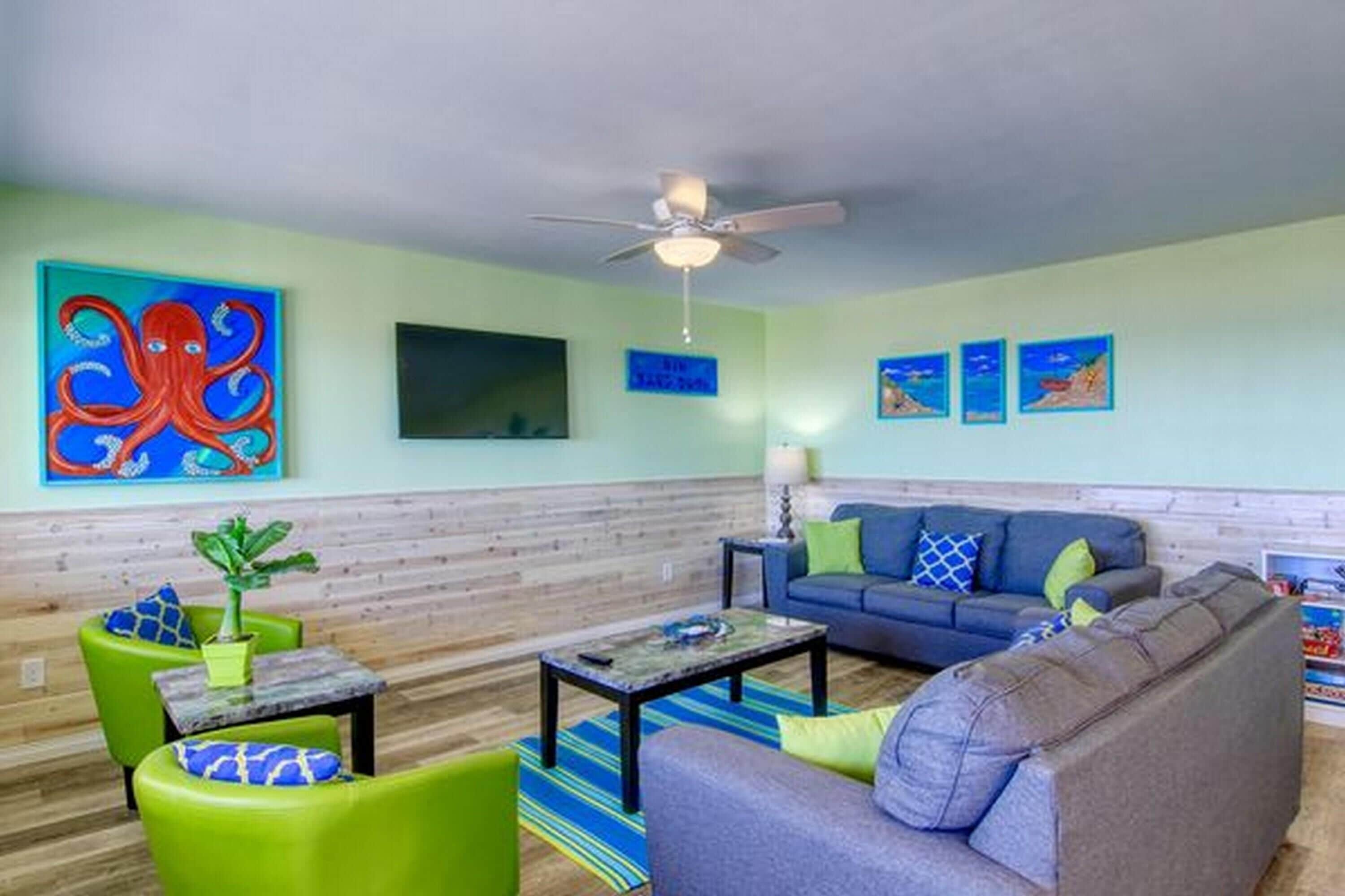 A living room with a green sofa, a blue sofa, a coffee table, and a ceiling fan.