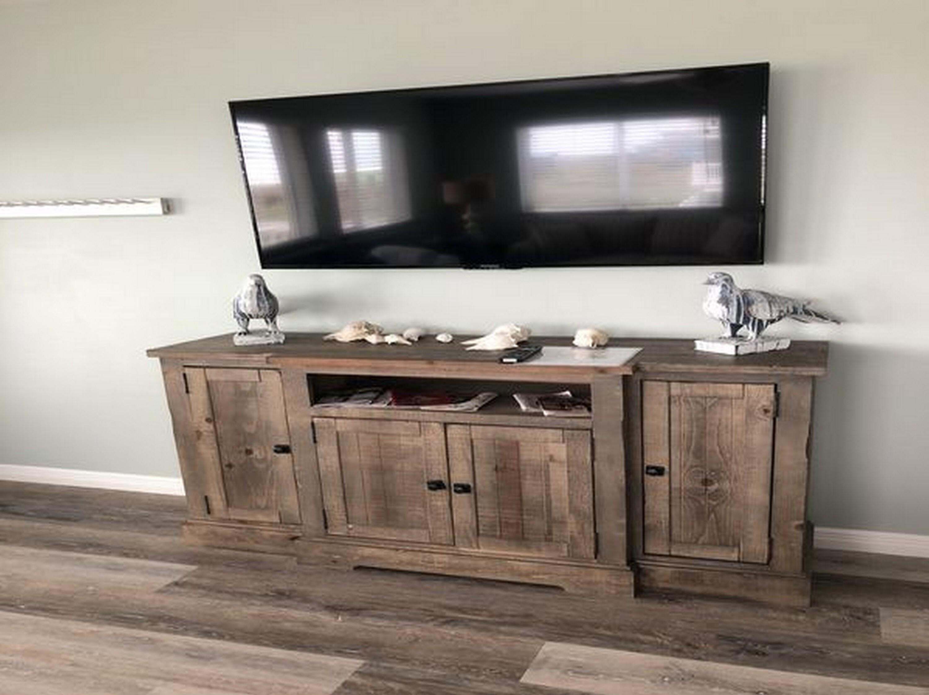 A wooden entertainment center with a flat-screen TV mounted above it.