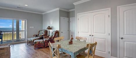 A dining area with a table and chairs, a view through a glass door, and a white door in the background.