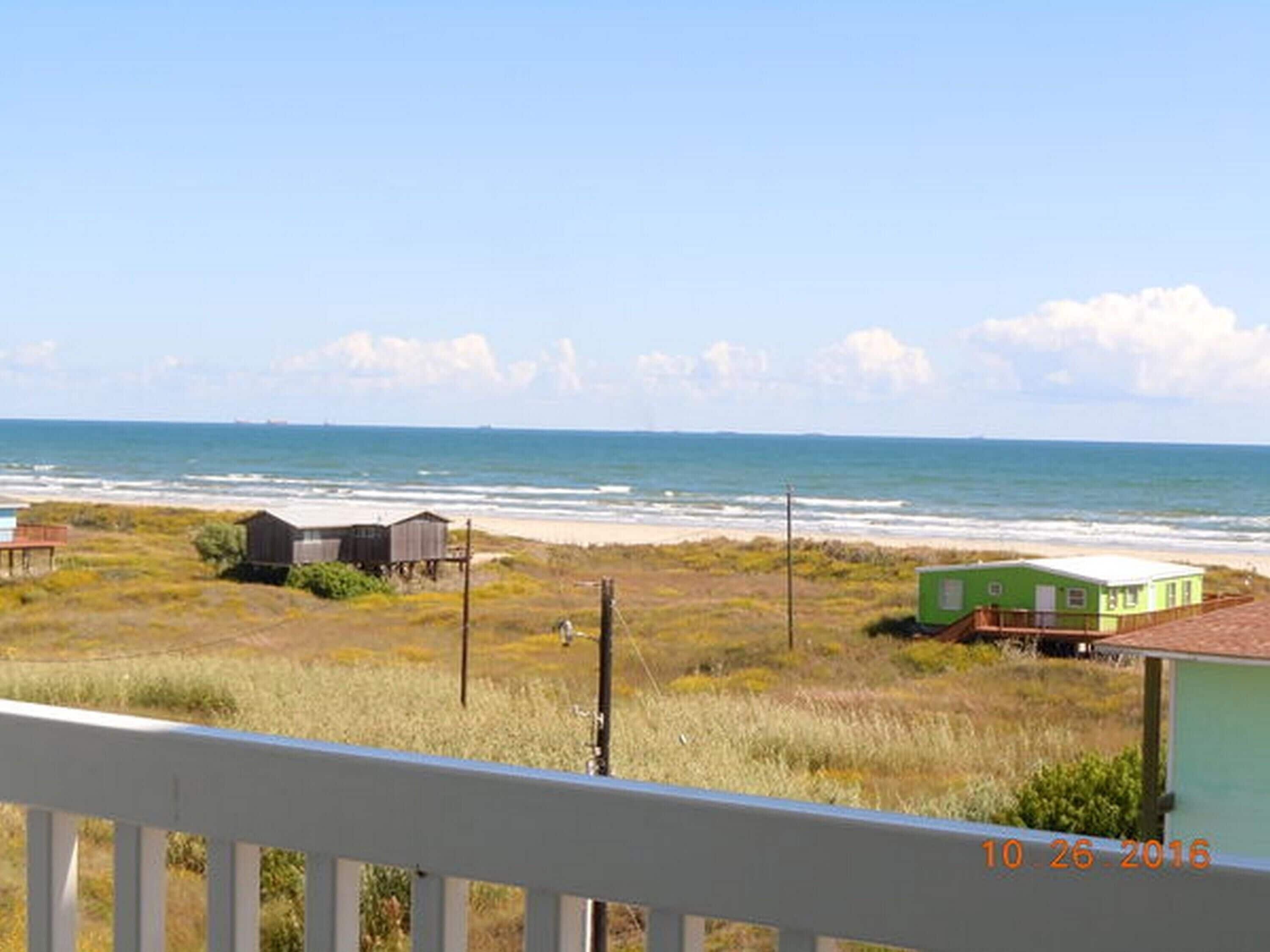 Vista costera con playa, una estructura verde y un edificio de madera.