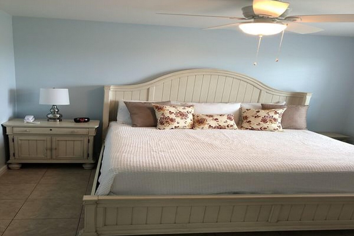 A bedroom with a bed, a nightstand, a lamp, and a ceiling fan.