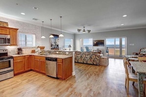 A spacious kitchen with wooden cabinets, a built-in microwave, and a dishwasher. There is a dining area with a table and chairs, and a large window offering a view of the outdoors.