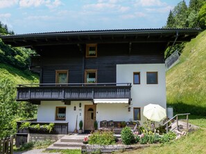 Ein zweistöckiges Gebäude mit Balkon, Tür und kleinem Garten.