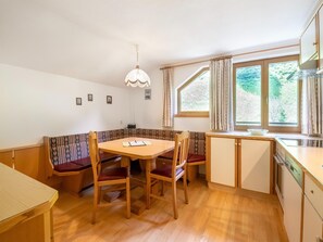 Une cuisine de taille réduite avec un coin repas, des meubles en bois et une fenêtre agrémentée de rideaux.