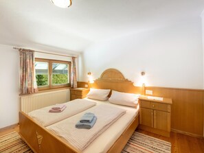 Ein Schlafzimmer mit einem Bett, zwei Nachttischen, einem Fenster mit Vorhängen und einem Kopfteil.