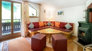 A cozy room with a built-in bench seating area, a table, and a wood-burning stove. - Chalet in Tirol by Zillertal Ski Slopes (Brandberg)