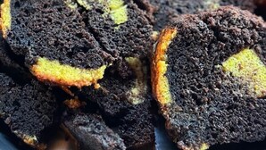 Un plateau de parts de gâteau au chocolat, coupées en tranches, avec une garniture jaune.