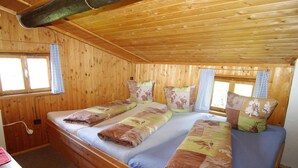 A wooden cabin room with two beds, a desk, and a window with curtains. - Quaint Mountain Hut in Hippach With Garden and Barbeque (Hippach)