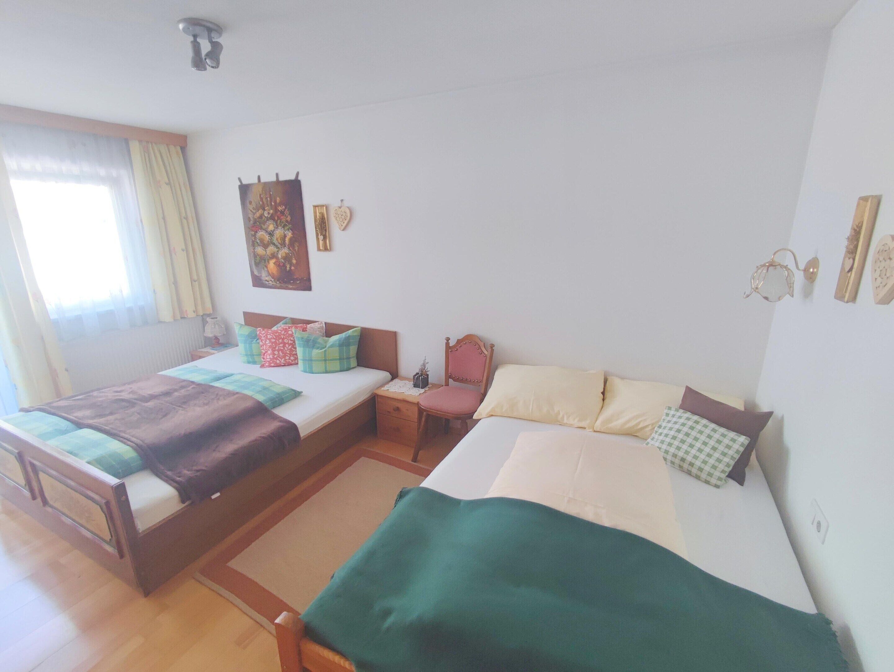 A double bed with a wooden frame, a bedside table, and a chair.