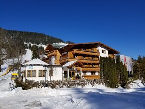 Un edificio in legno a più piani con balconi, un ristorante e una seggiovia sullo sfondo.