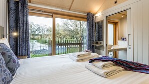 Ein Schlafzimmer mit einem großen Bett, ein Badezimmer mit Spiegel und Waschbecken sowie ein Gartenblick durch eine Schiebetür.