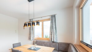 Ein moderner Essbereich mit einem Holztisch, einer grauen Sitzbank und Pendelleuchten.