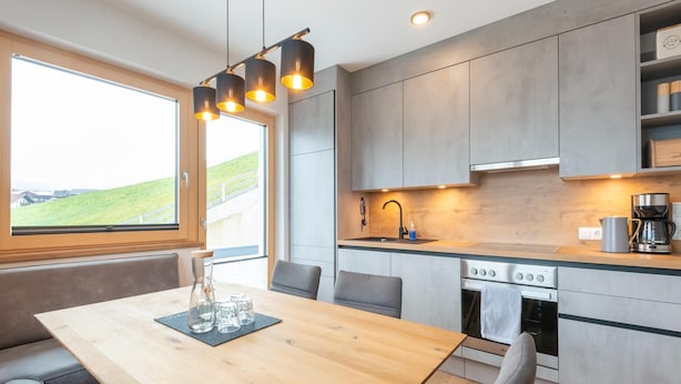 Eine moderne Küche mit einem Holztisch, grauen Stühlen und integrierten Geräten.