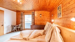 Puisesta materiaalista rakennettu mökkimäinen huone, jossa on sänky, työpöytä ja tuoli.
