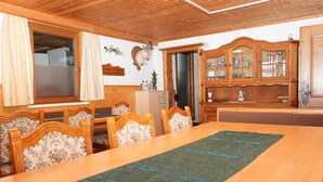 A dining area with a wooden table and chairs, a cabinet with glass doors, and a mounted animal head on the wall. - Group Holiday Home in Hippach With Dreamy Views (Hippach)