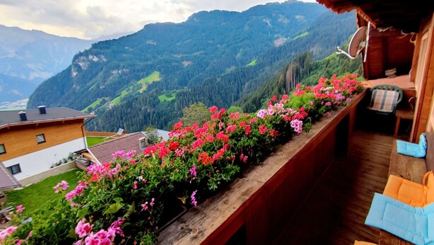 A balcony with a wooden railing, overlooking a mountainous landscape with houses and greenery. - Group Holiday Home in Hippach With Dreamy Views (Hippach)