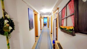A narrow hallway with a striped carpet, wooden doors, and a wall-mounted shelf with flowers. - Group Holiday Home in Hippach With Dreamy Views (Hippach)