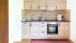 Uma cozinha compacta com armários de madeira, uma pia de aço inoxidável, uma cafeteira e um forno.