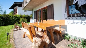 A wooden dining table with chairs, a stone patio, and a white building with a balcony. - Apartment in St. Johann in Tyrol With Terrace (Sankt Johann in Tirol)