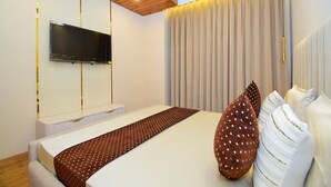 A modern bedroom with a large bed, a flat-screen TV mounted on the wall, and a curtain with a lighted drape. - Cliffton Valley by Dumnu Homes (Shimla)