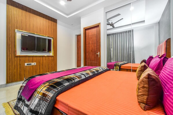 A modern hotel room with a large bed, a television, a wooden panel wall, and a ceiling fan. - Cliffton Valley by Dumnu Homes (Shimla)