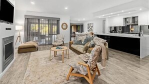 Una sala de estar moderna con sofá, sillón, mesa de centro y chimenea.