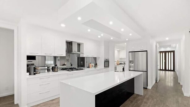 Una cocina moderna con armarios blancos, una isla grande y una encimera negra elegante.
